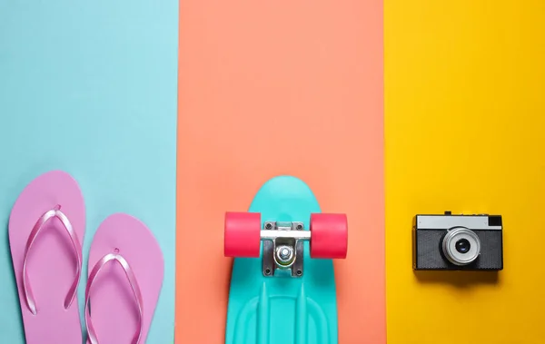 ヒップスターの衣装 レトロなカメラでスケートボード 色の背景にフリップフロップ 創造的なファッションミニマリズム 流行の古いファッショナブルなスタイル 最小限の夏の楽しみ 音楽の概念 トップ表示 — ストック写真