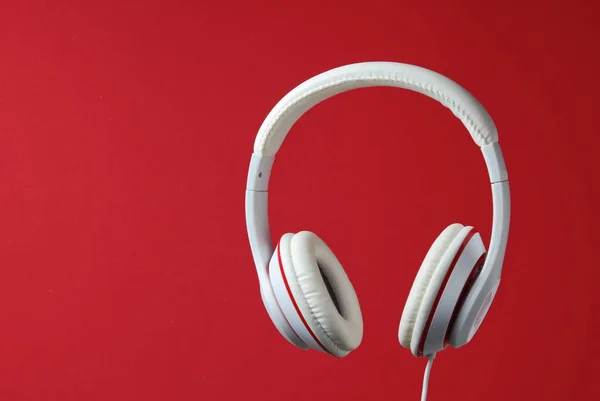 White classic wired headphones isolated on red background. Retro style. Minimalistic music concept.