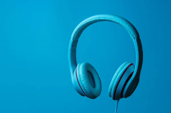 Classic wired headphones with blue neon light. Retro style. Minimalistic music concept.