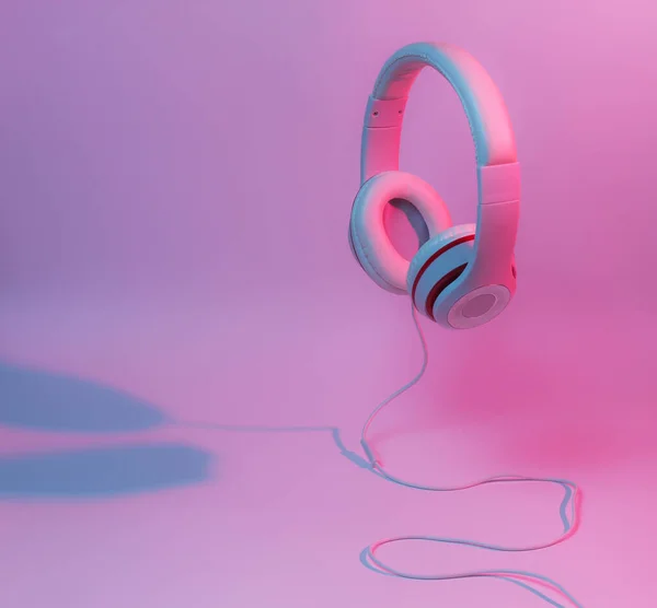 Classic wired headphones with gradient blue pink neon light. Retro style.Retro wave. 80s. Minimalistic music concept.