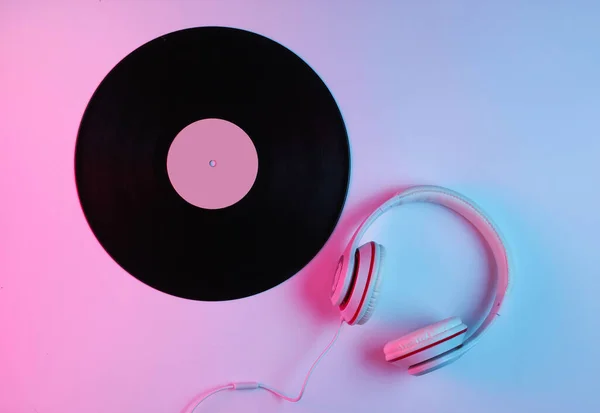 复古风格的音乐概念 经典耳机 带梯度粉色蓝色霓虹灯的乙烯唱片 流行文化 顶部视图 — 图库照片
