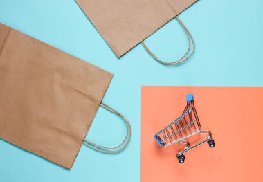 Renkli arka planda alışveriş arabası ve kese kağıdı olan bir model. Mutlu müşteri konsepti. İnternet alışverişi. İnternetteki mağaza. Tüketim, yaşam tarzı 