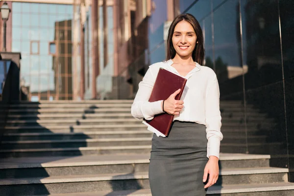 Young attractive business woman in a blouse and a skirt holding folder. Business concept. Modern work