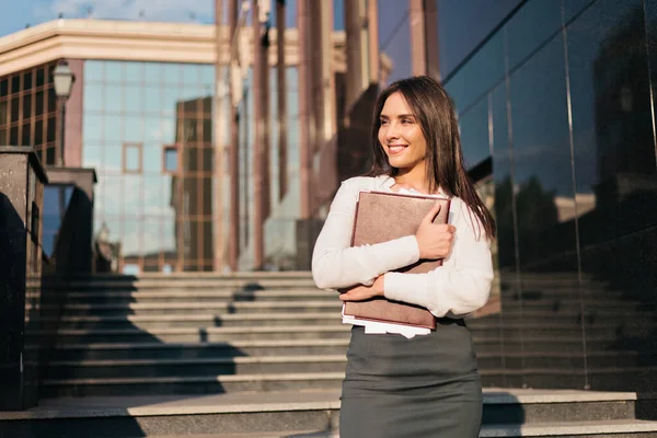 Young attractive business woman in a blouse and a skirt holding folder. Business concept. Modern work