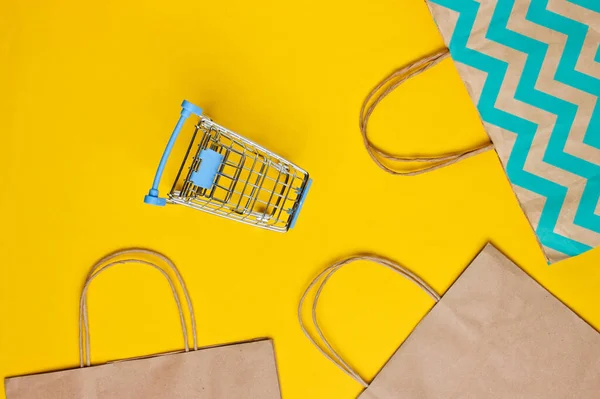 Mockup with shopping cart and paper bag on yellow background. Happy customer concept. Internet shopping. Online store. Consumerism, lifestyle