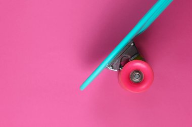 Pembe arka planda plastik mini kruvazör tahtası. Pastel renk eğilimi. Yaz eğlencesi. Gençlik minimalist konsepti. Üst görünüm