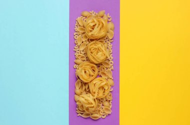 Renkli arka planda farklı çiğ İtalyan makarnaları. Minimalizm gıda konsepti. Boşluğu kopyala