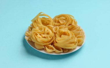 Mavi arka planda farklı çiğ İtalyan makarnaları..