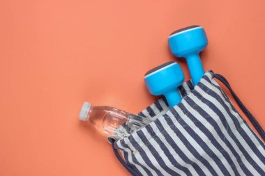 Mercan arka planında spor kıyafeti olan çizgili spor çantası. Spor hala hayat. Üst görünüm.