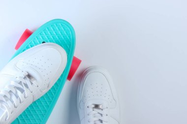 Plastik kruvazör tahtasındaki beyaz spor ayakkabılar. Beyaz arka plan. Üst görünüm