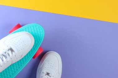 Plastik kruvazör tahtasındaki beyaz spor ayakkabılar. Pastel renk arkaplanı. Üst görünüm