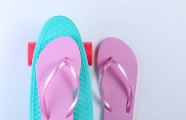 Parmak arası terlikler ve beyaz arka planda plastik kruvazör tahtası. Yaz eğlencesi. Üst görünüm