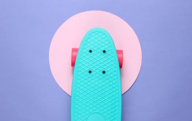 Mor arka planda pembe pastel bir daireyle kruvazör tahtası. Gençlik hipster konsepti. Yaz eğlencesi. Üst görünüm