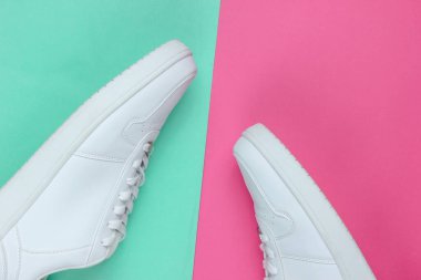 Pembe neon arka planda beyaz spor ayakkabılar. Gençlik hipster konsepti. Üst görünüm