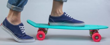 Gençlik hipster konsepti. Kotlu kadın bacakları ve kruvazörde spor ayakkabıları. Stüdyoda beyaz arka planda. Yaz eğlencesi