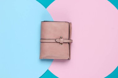 Arka planda pembe pastel dairesi olan zarif kadın cüzdanı. Yaratıcı minimalist moda natürmort. Üst görünüm