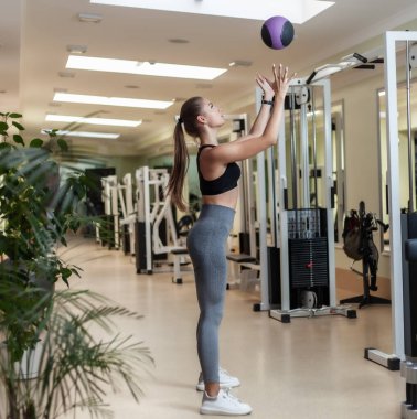 İşlevsel Eğitim Konsepti. Spor kıyafetli genç bir kadın spor salonunda tıp topu kusuyor.