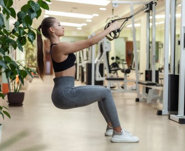 Slim fit kadın spor salonunda spor kemerleriyle antrenman yapıyor. Sağlıklı yaşam tarzı kavramı. Fonksiyonel eğitim
