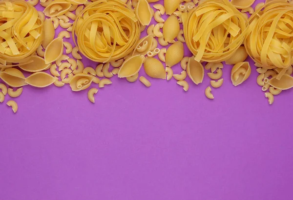 不同类型的意大利生面食 背景是紫色的 顶部视图 复制空间 — 图库照片