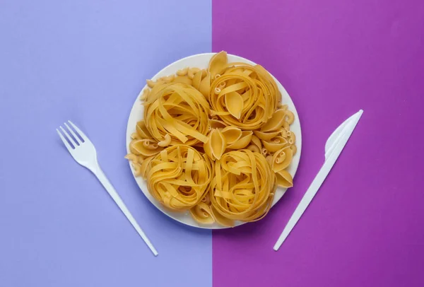 Diferentes Tipos Macarrão Italiano Cru Uma Placa Garfo Faca Fundo — Fotografia de Stock