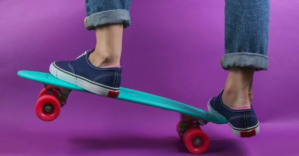 年轻嬉皮士的概念 穿着牛仔裤和运动鞋的女性腿在工作室的游轮板上穿着紫色背景的衣服 夏天快乐 — 图库照片