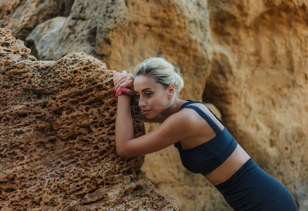 野生のビーチで石にもたれてスポーツウェアの疲れフィットネス女性の肖像画 屋外トレーニングコンセプト — ストック写真