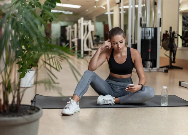 Jonge Sportvrouw Sportkleding Met Behulp Van Smartphone Tijdens Het Zitten — Stockfoto