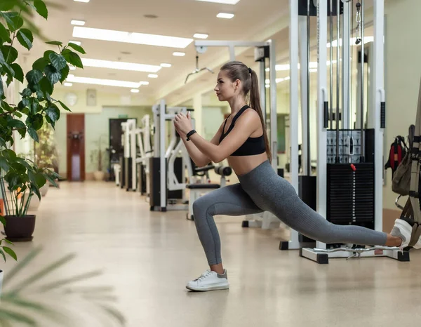 Slim fit kadın spor salonunda spor kemerleriyle antrenman yapıyor. Sağlıklı yaşam tarzı kavramı. Fonksiyonel eğitim