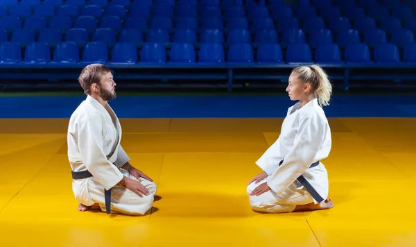 Martial arts. Sparing Portners. Sport man and woman greet each other while sitting in sports hall