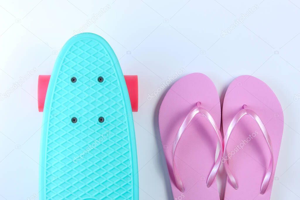 Flip flops and plastic mini cruiser board on white background. Summertime fun. Top view