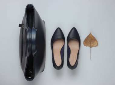 Sonbahar koleksiyonu. Deri yüksek topuklu ayakkabılar, arka planda kuru sonbahar yaprağı olan çanta. Stüdyo çekimi. Üst görünüm