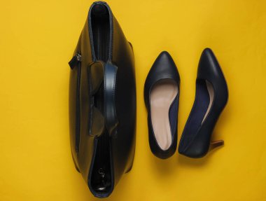 Deri yüksek topuklu ayakkabılar, sarı arka planda çanta. Stüdyo moda çekimi. Üst görünüm