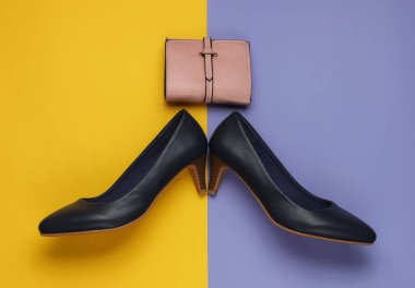 Deri yüksek topuklu ayakkabılar, sarı mor arka planda cüzdan. Stüdyo moda çekimi. Üst görünüm