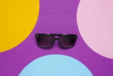Mor arka planda renkli kağıt daireli şık güneş gözlükleri. Düz moda natürmort hayat. Üst görünüm