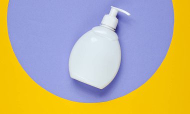 Geometrik şekilli renkli kağıt arka planda bir şişe sıvı sabun. Duş jeli, şampuan. Pop sanat tarzı. Üst görünüm