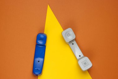 Geometrik şekilli renkli kağıt arka planda üç Retro telefon ahizesi. Popüler kültür. 80 'ler. Minimalist moda çekimi. Üst görünüm