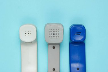 Mavi arkaplanda üç tane eski telefon var. Üst görünüm
