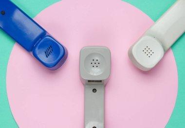 Mavi arka planda pembe renkli üç adet Retro telefon ahizesi. Popüler kültür. 80 'ler. Minimalist moda çekimi. Üst görünüm