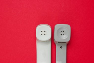 Kırmızı arkaplanda iki eski telefon var. Minimalizm. Üst görünüm