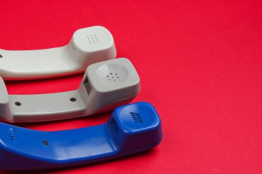 Kırmızı arkaplanda üç tane eski telefon var. Minimalizm. Merkezi ara. Yardım hattı.