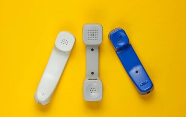Sarı arkaplanda üç tane eski telefon var. Üst görünüm