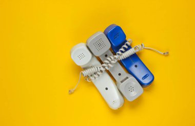 Sarı kabloya sarılı üç ofis telefonu tüpü. Çağrı merkezi, yardım hattı kavramı