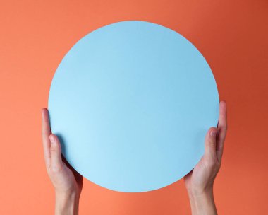 Eller mercan zemin üzerinde mavi bir daire tutar. Boşluğu kopyala