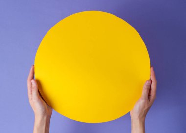 Eller mor arka planda sarı daireyi tutar. Boşluğu kopyala