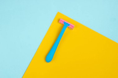 Mavi-sarı arka planda plastik mavi jiletler. Minimalist moda konsepti. Üst görünüm
