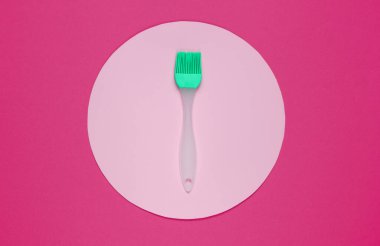 Mutfak fırçası pembe arkaplanda, ortası pastel renk çemberiyle. Üst Manzara. Minimalizm