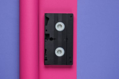 Kağıt kaplama arka planda video kaset. Pastel renk eğilimi, minimal retro 80 'lerin natürmortu. Üst görünüm