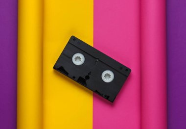 Kağıt kaplama arka planda video kaset. Pastel renk eğilimi, minimal retro 80 'lerin natürmortu. Üst görünüm