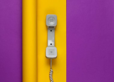 Telefon ahizesi sarılıp sarmalanmış mor kağıt arka planda. Renk trendi, minimalist durağan yaşam. Üst görünüm