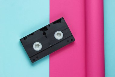 Kağıt kaplama arka planda video kaset. Pastel renk eğilimi, minimal retro 80 'lerin natürmortu. Üst görünüm